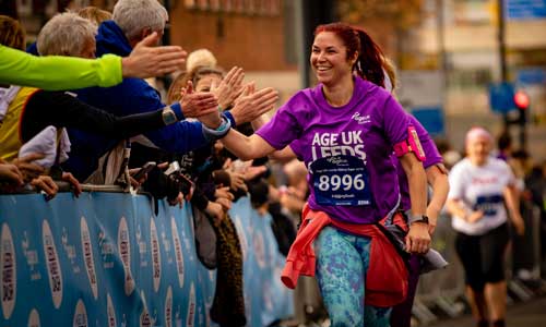Woman giving high fives to the crowd whilst running in the 168官方澳洲的幸运五结果体彩网 Leeds Abbey Dash
